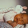 Lucia a rejoint le concours — aidez-le/la à gagner de superbes lots ! baby, sleeping, plush_toy, bunny, blanket, floral_pattern, infant, peaceful, soft_lighting, cute, child, resting, indoors, cozy, pink_clothing, newborn, portrait, hand, face, calm