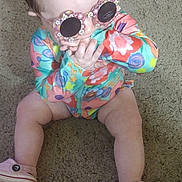 Raelynn joined the competition — help win amazing prizes! baby, child, sunglasses, colorful_clothing, carpet, sitting, hand, pony_tail, pink_shoes, indoor, cute, infant, footwear, patterned_clothing, person, young_child, floor, playful, accessory, casual