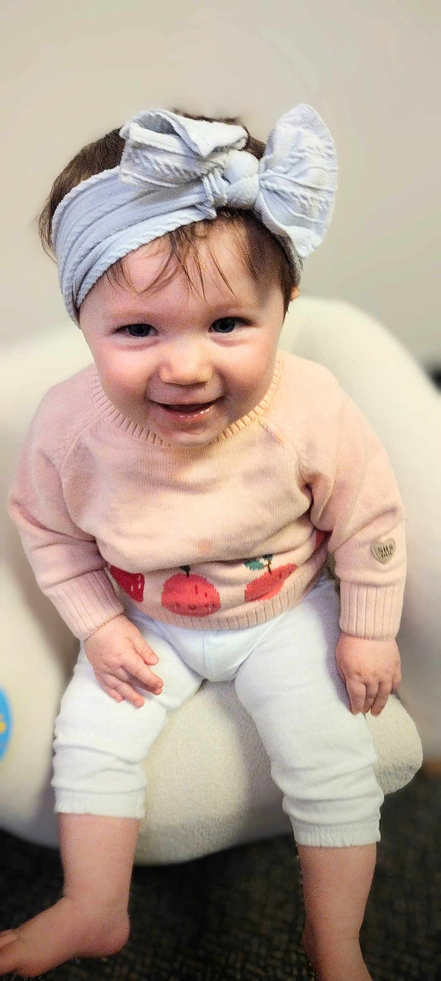 Raelynn joined the competition — help win amazing prizes! baby, child, smile, headband, bow, sweater, white_pants, sitting, indoor, cute, face, person, infant, happy, young_child, clothing, furniture, soft_texture, portrait, baby_girl