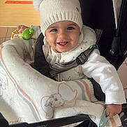 Elina a rejoint le concours — aidez-le/la à gagner de superbes lots ! baby, child, smiling, stroller, blanket, hat, pom_poms, indoor, happy, cute, clothing, toddler, toy, person, seatbelt, floor, footwear, warm_clothing, infant, portrait