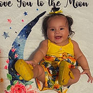 Kaylee joined the competition — help win amazing prizes! baby, child, smiling, yellow_clothing, floral_pattern, blanket, crescent_moon, flowers, happy, cute, infant, portrait, indoors, playful, colorful, footwear, headband, person, skin, face