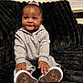 Kemora is registered to the contest to win money with this photo: baby, child, smile, sneakers, gray_outfit, pink_bow, black_couch, plush, indoor, portrait, cute, hands, feet, happy, person, young_child, cozy, seated, expression, home