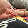 baby, sleeping, close_up, face, cheeks, arm, skin, resting, person, indoors, comfort, peaceful, child, couch, blanket, casual, soft_light, relaxation, human, toddler
