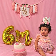 Meilani joined the competition — help win amazing prizes! baby, backdrop, balloons, birthday, birthday_cake, cake_stand, child, crown, curly_hair, decoration, dress, floral, gold, number_six, party, pink, portrait, sitting, smiling, studio