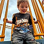 child, boy, playground, yellow_bars, hot_wheels_tshirt, ripped_jeans, outdoor, cloudy_sky, smiling, playing, person, hands, metal_structure, casual_clothing, happy, daylight, park, friends, fun, jeans