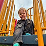 Uhtred is registered to the contest to win money with this photo: child, playground, yellow_bars, ripped_jeans, blue_socks, smiling, outdoor, play_equipment, casual_clothing, young_boy, cloudy_sky, metal_structure, park, happy, recreation, fun, daylight, person, jeans, footwear