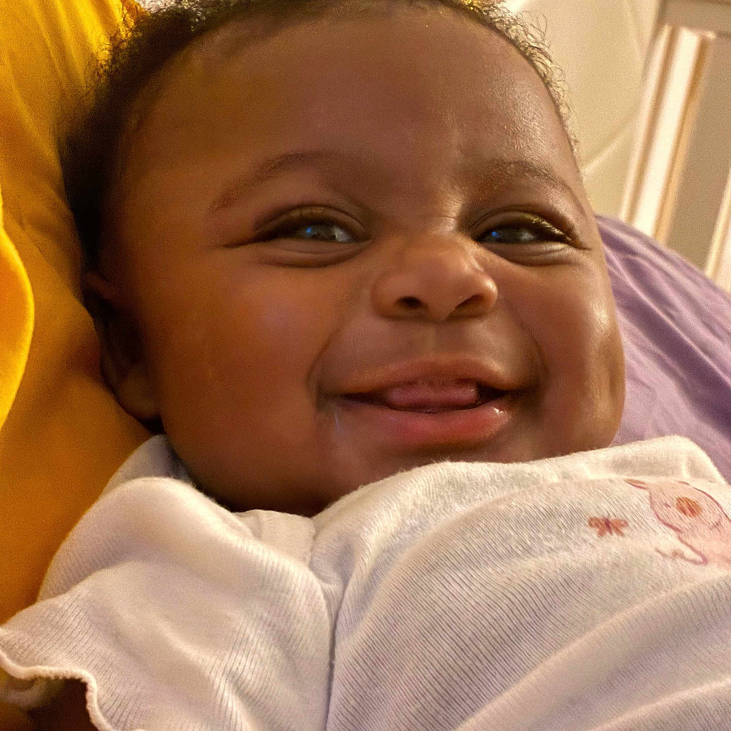 Karmin is registered to the contest to win money with this photo: baby, candid, child, closeup, curly_hair, cute, expression, face, happy, head, indoors, infant, person, portrait, skin, smiling, soft_light, tongue, white_clothing, young_child