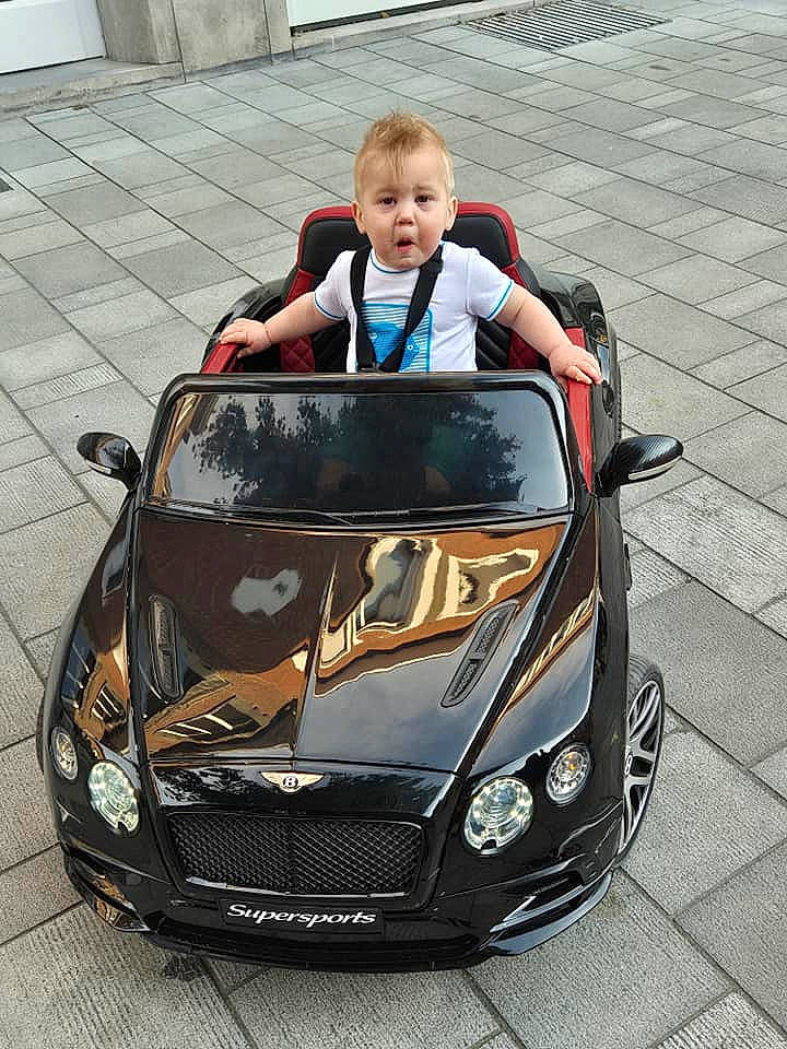 Tiyo participe au concours pour gagner de l'argent avec cette photo : automotive_design, automotive_exterior, automotive_fog_light, automotive_lighting, automotive_mirror, automotive_wheel_system, bumper, car, fender, grille, headlamp, hood, motor_vehicle, person, personal_luxury_car, photograph, rim, tints_and_shades, toddler, vehicle