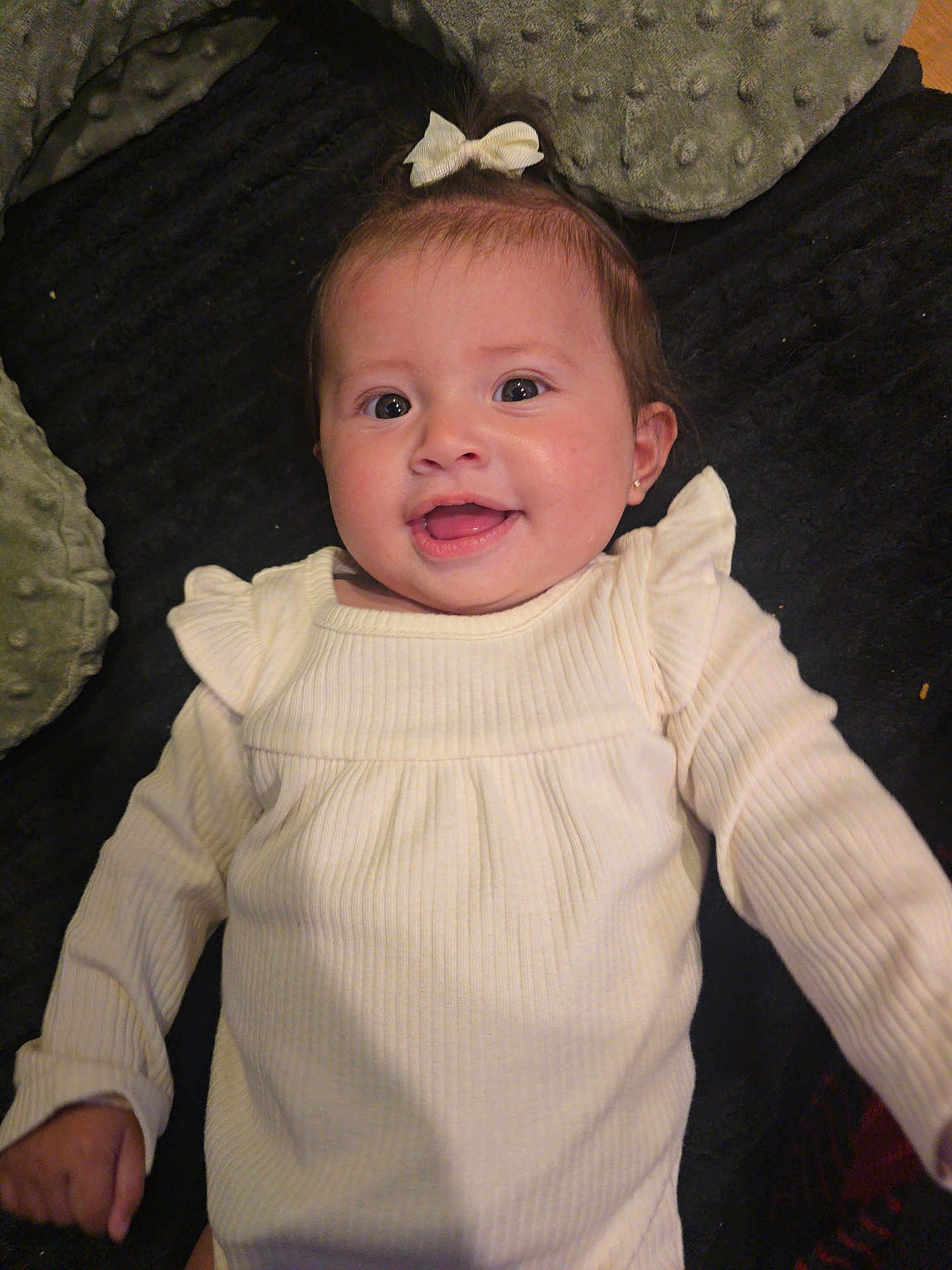 Anniliah joined the competition — help win amazing prizes! baby, blanket, bow, child, cushion, cute, expression, face, happy, head, indoors, infant, long_sleeves, lying_down, person, portrait, skin, smiling, white_clothing, young_child