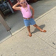 Aurora is registered to the contest to win money with this photo: braids, brown_shoes, building, casual, child, concrete, confident, denim_shorts, fashion, girl, glass_doors, necklaces, outdoor, pink_sunglasses, pink_top, posing, posters, ribbons, sidewalk, summer