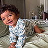 toddler, child, smiling, curly_hair, crawling, bed, pillow, sweater, indoor, happy, person, young_child, face, home, lamp, blanket, furniture, cozy, cute, playful