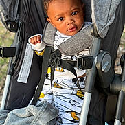 Isis joined the competition — help win amazing prizes! toddler, child, stroller, baby, blanket, clothing, cartoon_print, seatbelt, outdoor, person, portrait, curious, expression, baby_clothes, gray_blanket, closeup, baby_face, infant, baby_girl_or_boy, casual