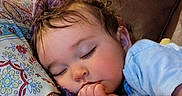Zoë joined the competition — help win amazing prizes! toddler, child, sleeping, thumb_in_mouth, blanket, pillow, patterned_pillow, curly_hair, blue_shirt, couch, indoor, resting, peaceful, face, closed_eyes, comfort, cozy, young_child, relaxation, home
