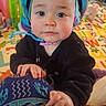 Zoë is registered to the contest to win money with this photo: baby, bright_colors, candid, casual, child, colorful, curious, face, floor, hand, headgear, helmet, indoor, infant, looking_at_camera, patterned_clothing, person, playmat, toy, young_child