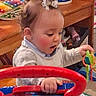 blue, candid, child, colorful, curly_hair, cute, engaged, green, happy, indoor, musical_instrument, person, pigtails, play, playroom, red, toddler, toy, white_sweater, wooden_furniture