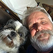Chewie is registered to the contest to win money with this photo: man, dog, beard, fluffy_dog, couch, smile, indoor, pet, portrait, white_hair, gray_hair, furniture, relaxed, closeup, companion, friendship, casual, home, happy, face