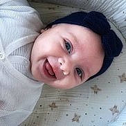 Aria participe au concours pour gagner de l'argent avec cette photo : baby, infant, smiling, headband, blue_eyes, blanket, swaddle, white_clothing, portrait, closeup, crib, fabric, star_pattern, button, mouth_open, tongue, happy, cute, newborn, face