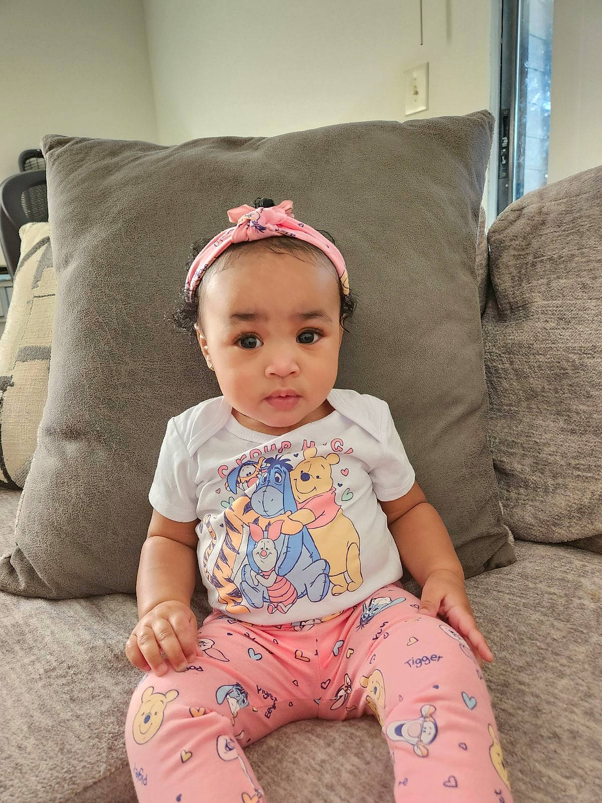 Dakotah is registered to the contest to win money with this photo: arm, baby, baby_toddler_clothing, child, comfort, couch, face, fashion_accessory, headband, human_leg, jewellery, knee, pattern, person, sitting, skin, sleeve, smile, t_shirt, thigh