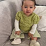 baby, child, comfortable, couch, cozy, cute, gray_couch, green_sweater, hands, indoors, knitwear, pigtails, pillow, portrait, sitting, smiling, soft_shoes, striped_pants, toddler, young_child