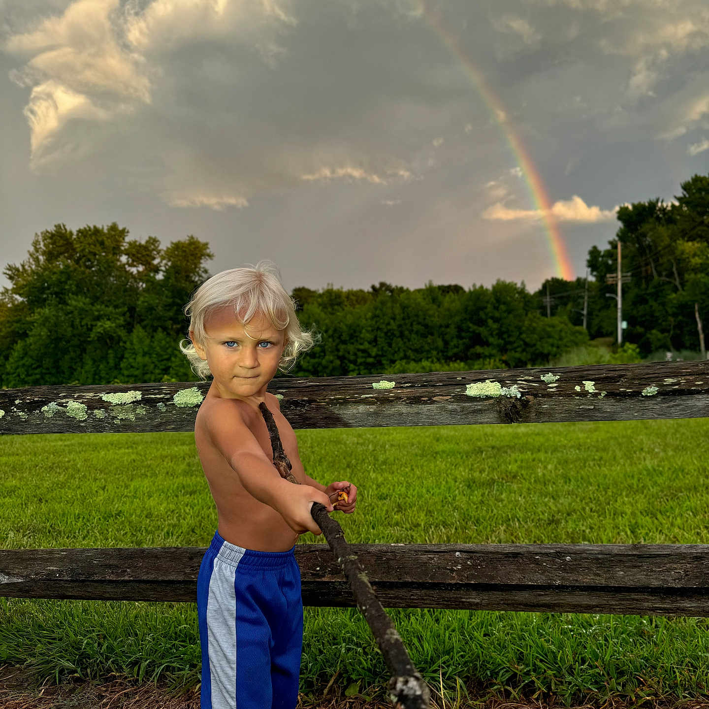 Dominick is registered to the contest to win money with this photo: bodypart, child, clothing, face, female, finger, girl, grass, hand, head, nature, outdoors, person, photography, plant, portrait, rainbow, shorts, sky, summer