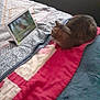 cat, tabby_cat, bed, blanket, tablet, technology, indoor, pet, furniture, cushion, quilt, animal, watching, resting, cozy, home, soft, striped, relaxed, device