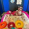 Isabella is registered to the contest to win money with this photo: baby, child, sunglasses, heart_shaped, toys, rings, abc_blocks, quilt, colorful, pink, yellow, orange, red, blue, floor, wooden_floor, playroom, decorations, bee, flower