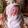 baby, closeup, cozy, cute, decor, flowers, headwear, indoor, infant, natural_light, newborn, peaceful, portrait, sleeping, smiling, soft_fabric, warm, white_cloth, wooden_bowl, wrapped