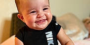 Miyla is registered to the contest to win money with this photo: baby, black_clothing, blanket, cheerful, child, cute, expression, face, feet, hand, happy, indoors, infant, nike, portrait, sitting, skin, smiling, soft, young