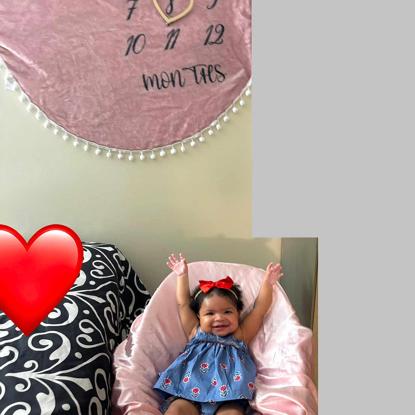 Ayla is registered to the contest to win money with this photo: baby, child, smiling, blue_dress, red_bow, pink_chair, pink_blanket, calendar, heart_shape, raised_hands, indoor, cushion, happy, person, furniture, decor, pattern, footwear_free, cute, red_heart_emoji