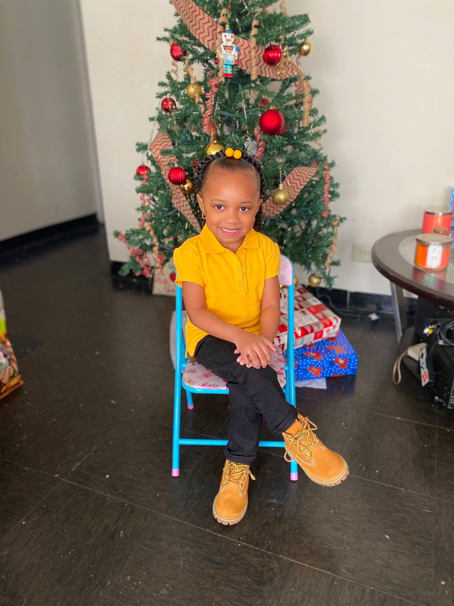 Amiyah joined the competition — help win amazing prizes! chair, child, christmas, christmas_decoration, christmas_eve, christmas_ornament, christmas_tree, event, evergreen, face, flooring, fun, holiday, holiday_ornament, joy, lap, ornament, person, plant, smile
