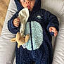 baby, infant, onesie, blue, plush_toy, cushion, face, hand, blanket, indoor, child, cute, portrait, expression, hooded_clothing, soft_texture, lying_down, curious, person, young