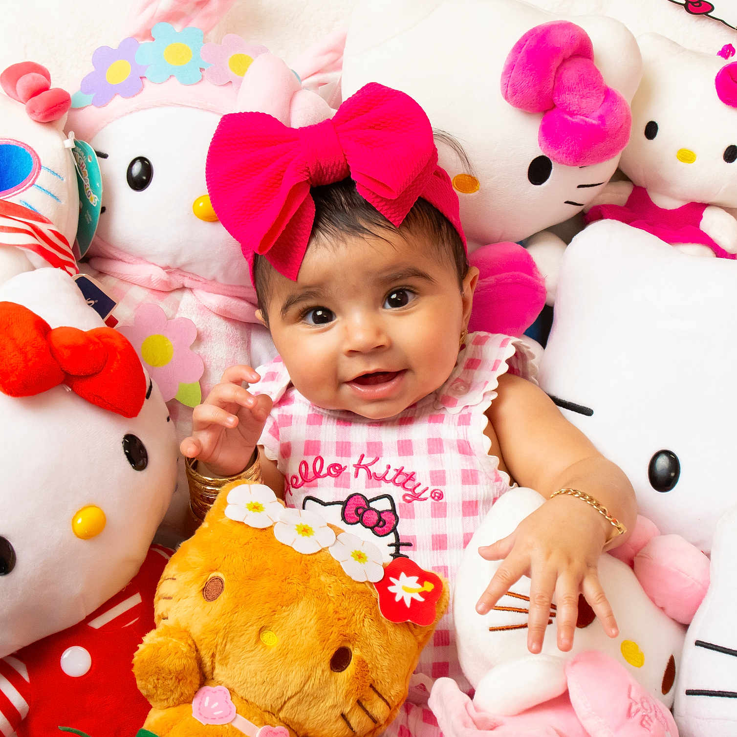 Reynesmae is registered to the contest to win money with this photo: baby, bracelet, child, clothing, cuddly, cute, girl, happy, headwear, hello_kitty, indoor, infant, pink_bow, playful, plush_toys, portrait, smiling, soft_toys, stuffed_animals, toy