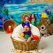 Reynesmae joined the competition — help win amazing prizes! baby, basket, plush_toy, seashell, underwater_theme, mermaid_costume, purple_bow, smiling, toys, stuffed_animal, photography, portrait, decor, child, studio, colorful, background, props, cute, happy