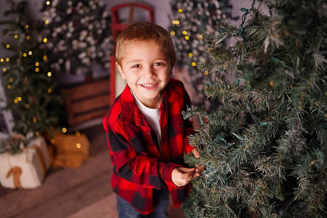 Jonathan is registered to the contest to win money with this photo: child, christmas, christmas_decoration, christmas_ornament, christmas_tree, flash_photography, hairstyle, happy, head, holiday, human_body, joy, lighting, people_in_nature, person, plant, smile, standing, toddler, tree