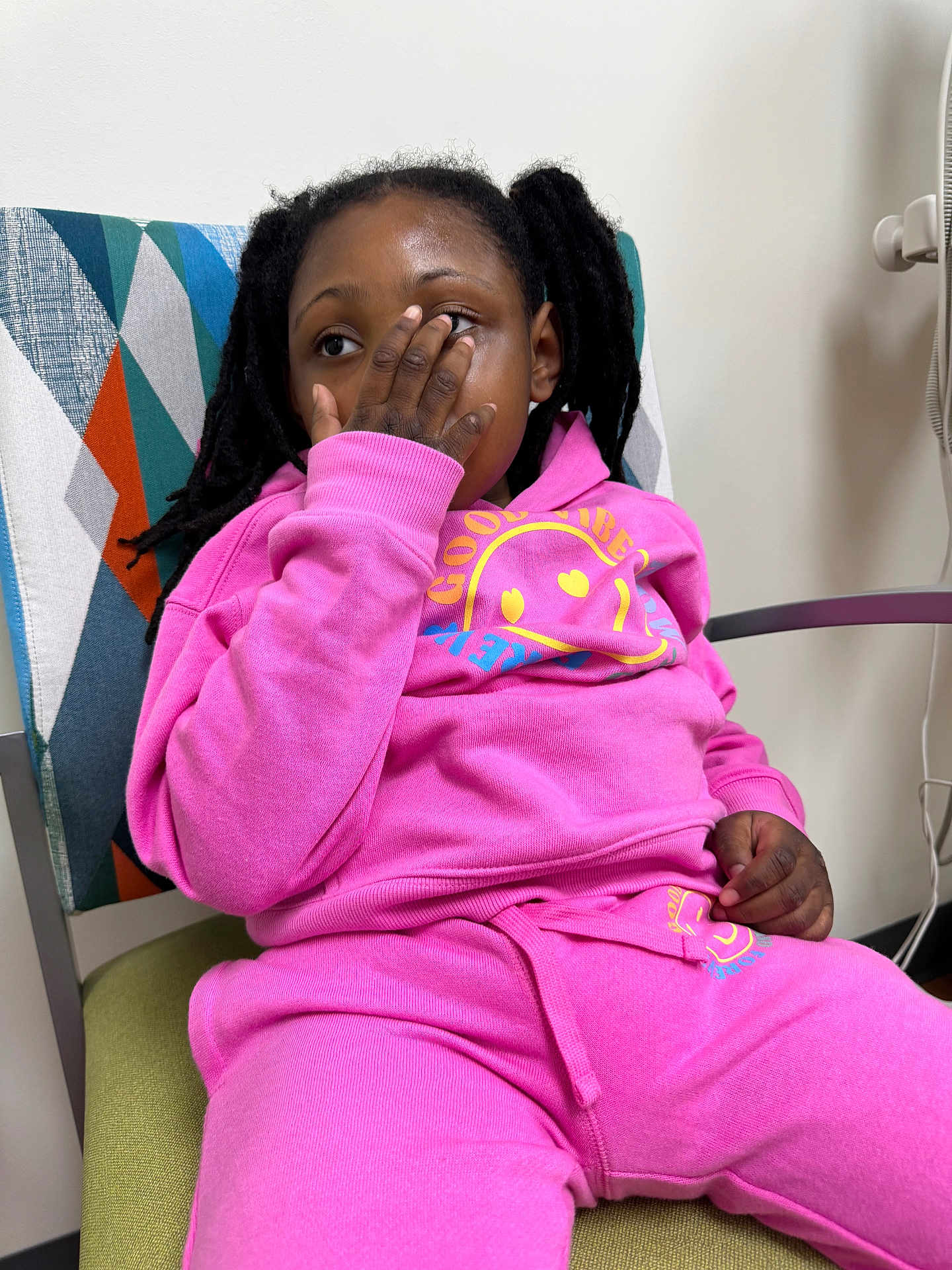Prayze joined the competition — help win amazing prizes! child, pink_tracksuit, sitting, chair, hand_on_face, indoor, geometric_pattern, casual_clothing, relaxed_pose, person, young, portrait, dreadlocks, colorful, furniture, expression, comfort, modern, home, playful