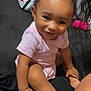 Kayley is registered to the contest to win money with this photo: baby, child, smiling, sitting, pink_onesie, curly_hair, indoor, couch, pillow, skin, foot, hand, happy, person, infant, cute, portrait, young, face, home