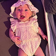 Bella Rose is registered to the contest to win money with this photo: baby, infant, smiling, pink_outfit, hat, pacifier, lying_down, happy, face, skin, hand, foot, bed, blanket, mesh, clothing, cute, child, one_person, indoors