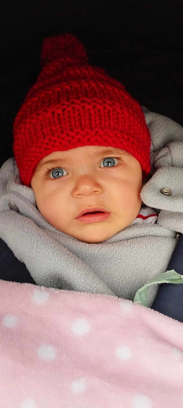 Lévi participe au concours pour gagner de l'argent avec cette photo : baby, child, red_hat, knit_hat, pom_pom, fleece, blanket, pink_blanket, polka_dots, blue_eyes, face, portrait, cozy, warm_clothing, infant, close_up, expression, indoor, soft_texture, cute