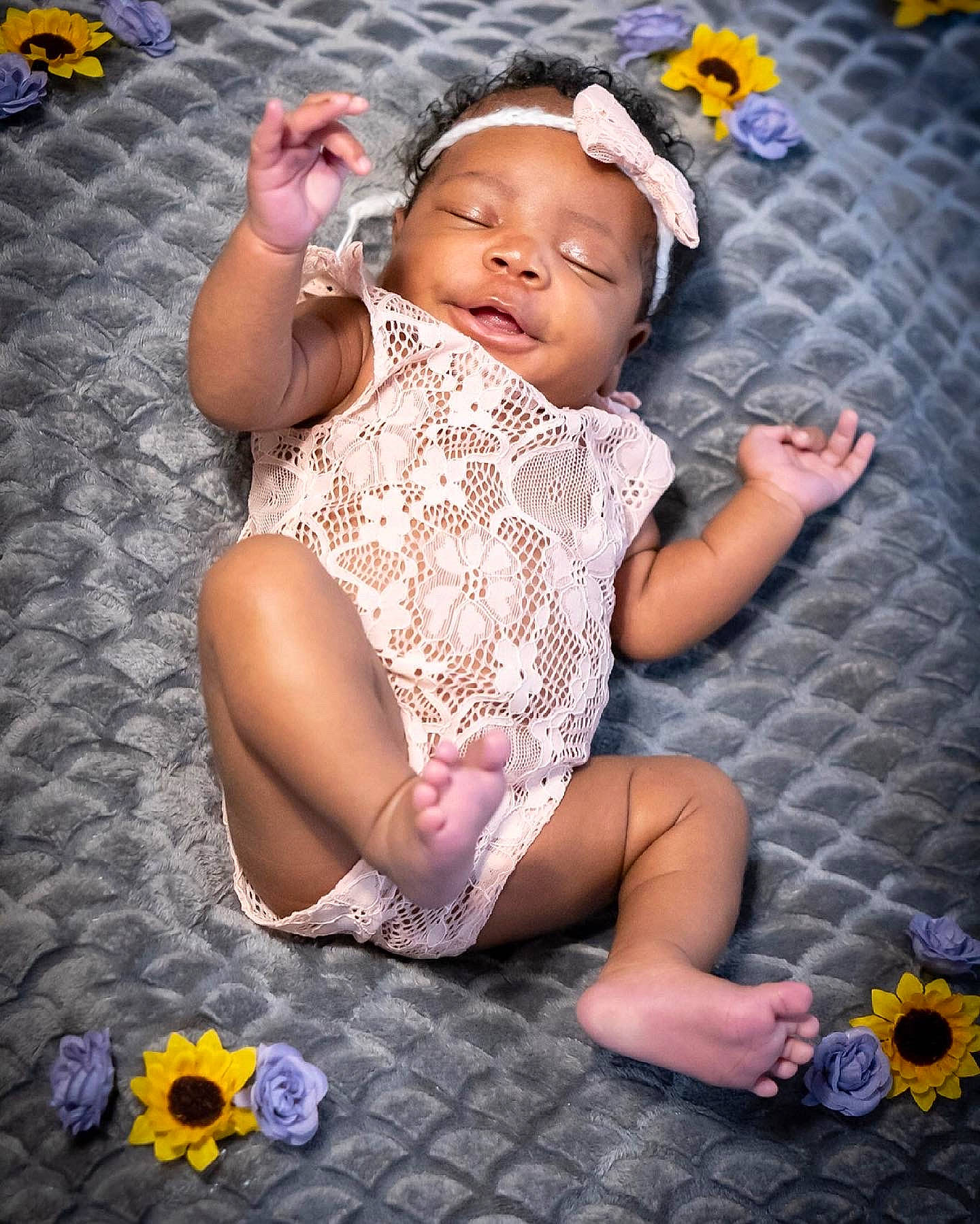River Sage is registered to the contest to win money with this photo: arm, baby, baby_toddler_clothing, blue, dress, face, finger, flash_photography, flower, grass, happy, headwear, leg, orange, people, people_in_nature, person, photograph, purple, skin
