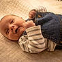 baby, infant, smiling, denim_overalls, striped_shirt, quilted_blanket, lying_down, happy, cute, child, face, skin, hand, clothing, portrait, indoors, soft_light, young, playful, expression