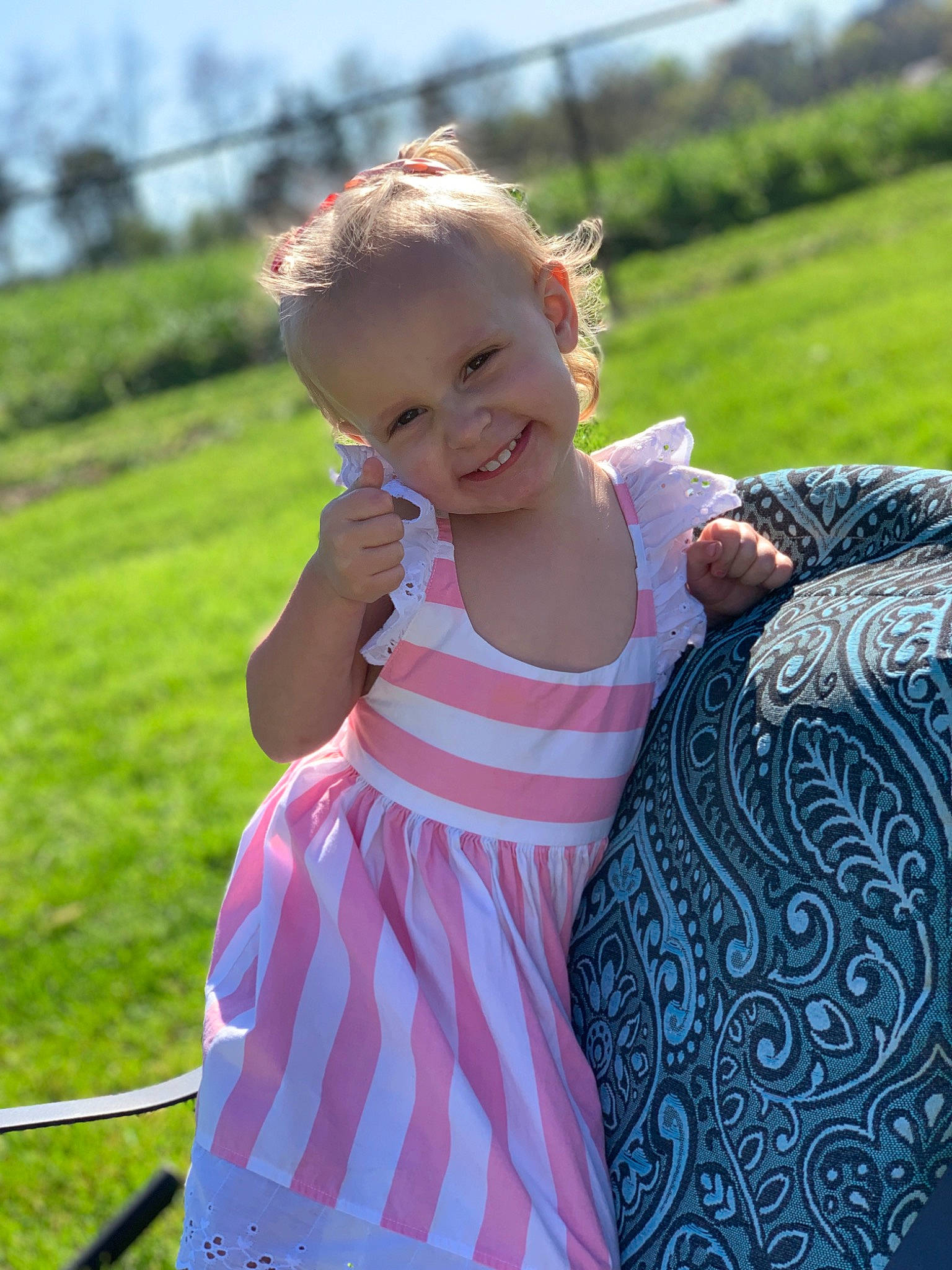 Kimber is registered to the contest to win money with this photo: baby_toddler_clothing, day_dress, dress, fun, grass, grassland, happy, joy, leisure, meadow, people_in_nature, person, pink, recreation, shoulder, sky, sleeve, smile, standing, summer