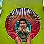 Jerzain Eden joined the competition — help win amazing prizes! toddler, child, playground, play_equipment, green, red, circle, smiling, socks, outdoor, fun, park, curly_hair, clothing, happy, sitting, baby, metal, plastic, daylight