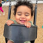 Jerzain Eden is registered to the contest to win money with this photo: toddler, child, swing, playground, smiling, curly_hair, happy, outdoor, park, wood_chips, bench, person, baby_swing, hand, face, clothing, green_sweater, shorts, daylight, fun