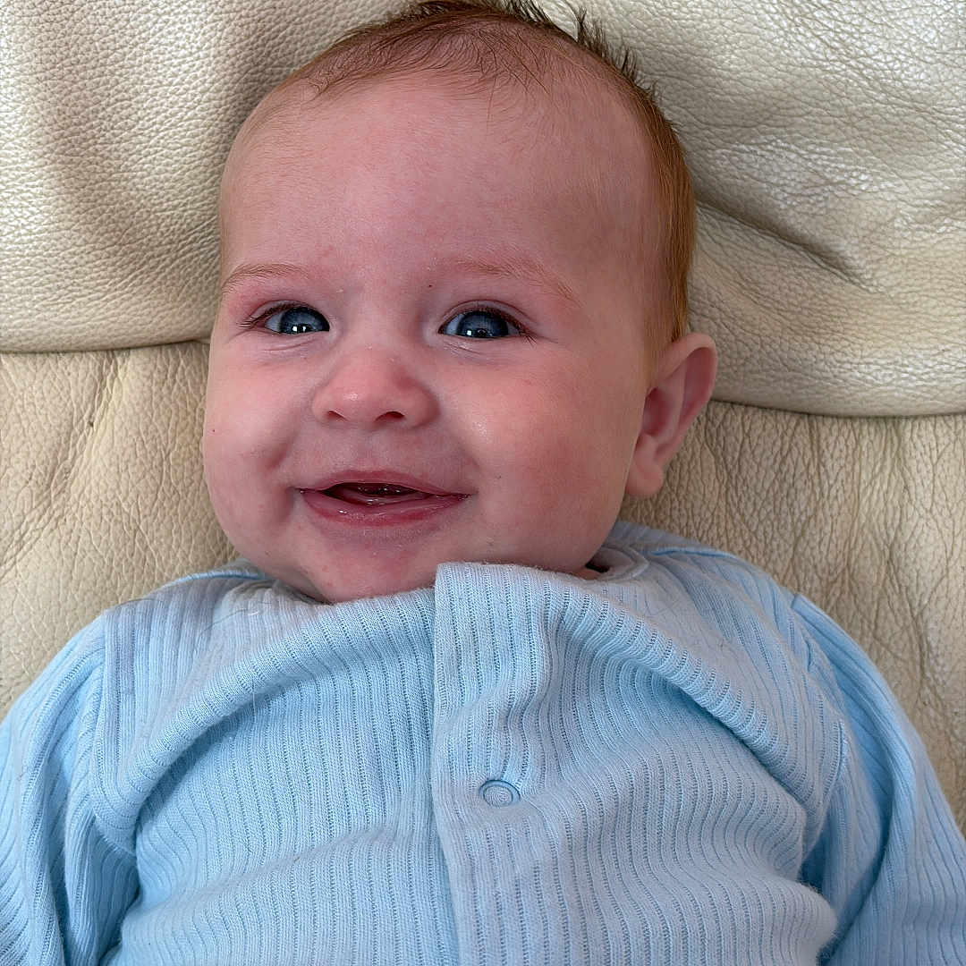 Noah-James joined the competition — help win amazing prizes! baby, blue_clothing, buttoned_shirt, child, cozy, cute, expression, eyes, face, happy, head, indoor, infant, leather_couch, mouth, portrait, sitting, skin, smiling, young_child