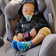Octavius is registered to the contest to win money with this photo: baby, car_interior, car_seat, child, clothing, comfort, cute, hoodie, infant, pacifier, peaceful, rest, safety, seat, seatbelt, sleeping, socks, toddler, travel, young_child
