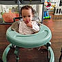 Octavius is registered to the contest to win money with this photo: child, toddler, baby, walker, toy, playpen, hardwood_floor, indoor, tongue_out, expression, face, sitting, onesie, seat, home_interior, heater, toy_cart, cinder_block, floor, wooden_floor