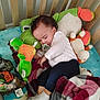 Octavius is registered to the contest to win money with this photo: baby, sleeping_baby, crib, plush_toy, frog_plush, pacifier, blanket, stuffed_animal, toddler, infant, socks, pillow, nursery, nap, candid, soft_toys, white_shirt, blue_pants, wooden_slats, cozy