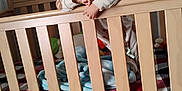 Octavius is registered to the contest to win money with this photo: baby, baby_bed, blanket, blue_blanket, child, crib, face, furniture, hand, infant, interior, pacifier_clip, pajamas, plaid_blanket, portrait, railing, smile, toddler, toy, wooden_crib