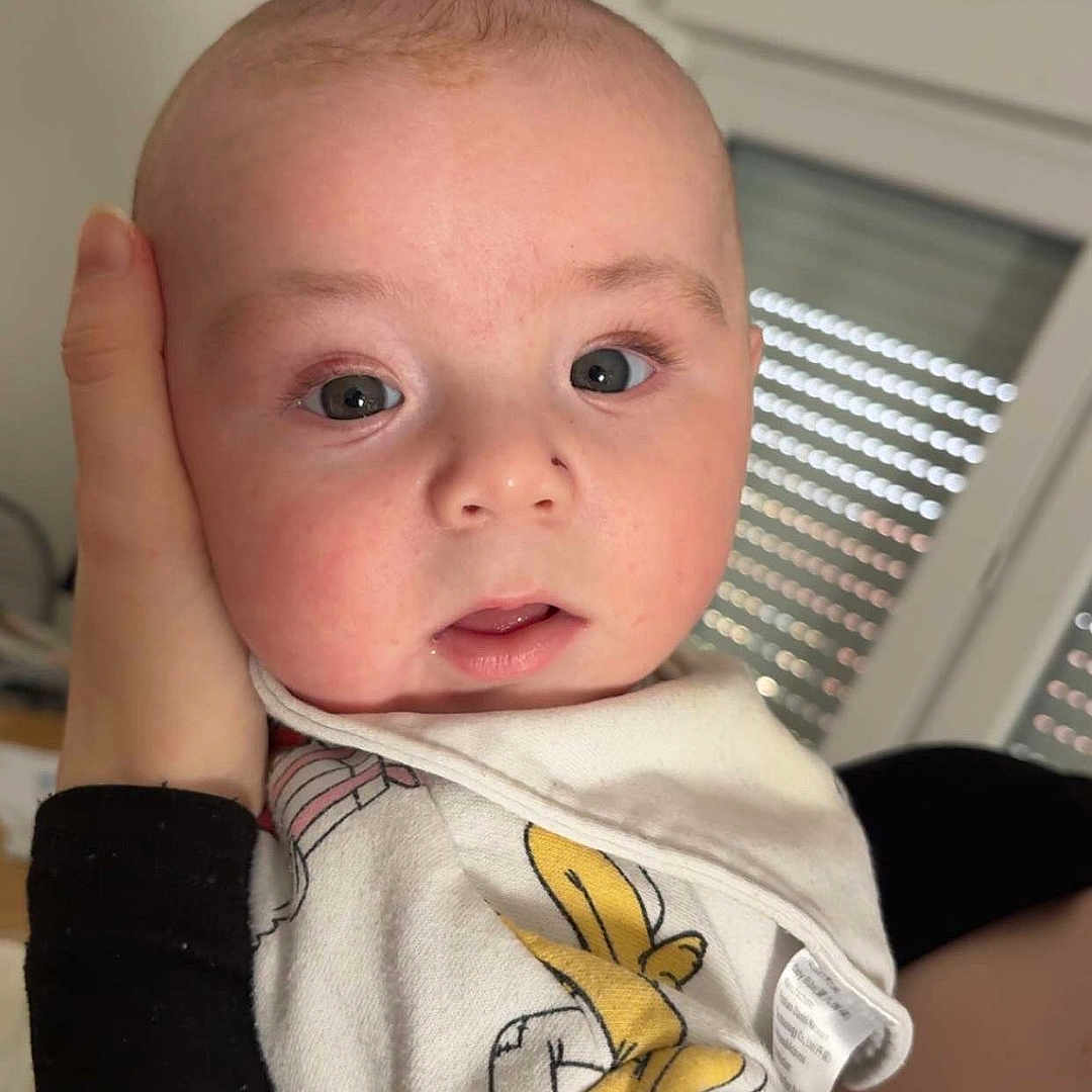 Elio a rejoint le concours — aidez-le/la à gagner de superbes lots ! baby, infant, child, face, hand, onesie, clothing, cartoon, indoor, person, portrait, cute, expression, skin, head, eyes, newborn, holding, human, toddler