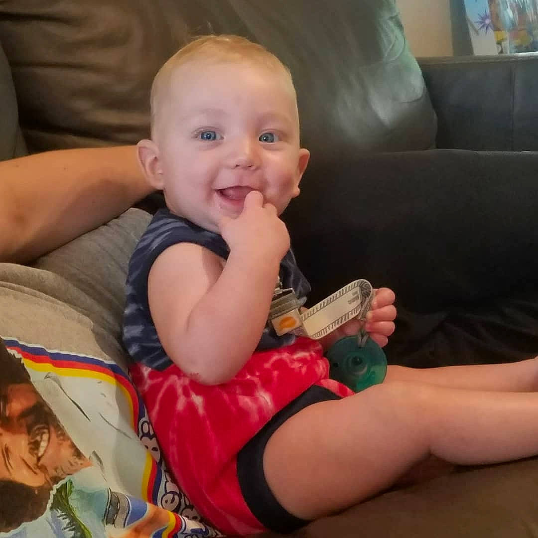 Pierce is registered to the contest to win money with this photo: arm, baby, cheek, child, eating, eye, finger, hand, head, leg, mouth, nail, person, play, sitting, skin, thigh, thumb, toddler